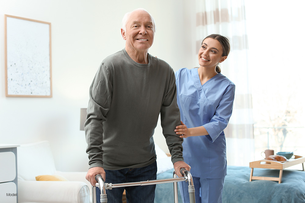 An elderly man using a walker with a nurse